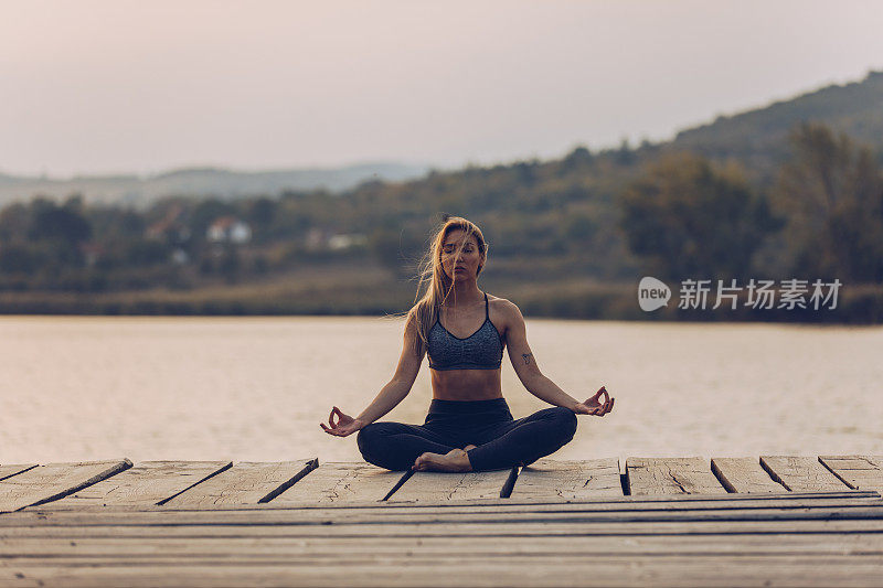 健康和运动的年轻女子在湖边做瑜伽