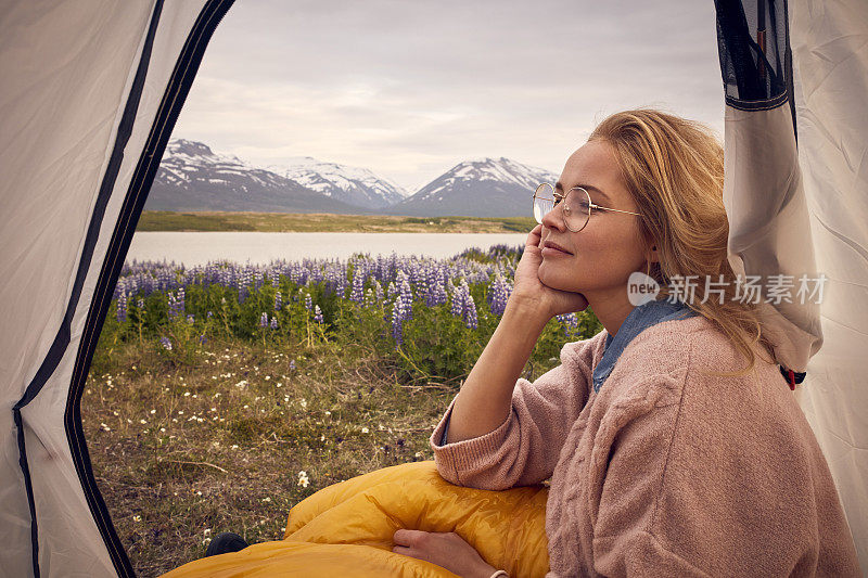 野外露营。一个在帐篷里欣赏风景的女人