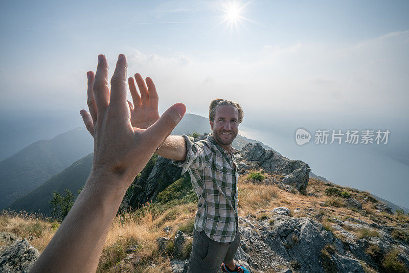 两个徒步旅行者在山顶击掌庆祝的个人视角