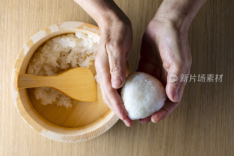 日本老妇人捧着饭团煮米饭