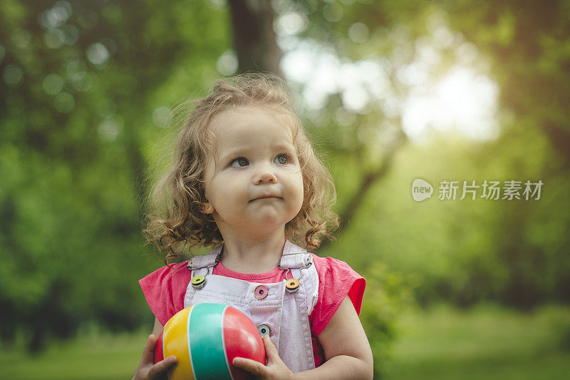 快乐的小女孩在夏天的公园玩球