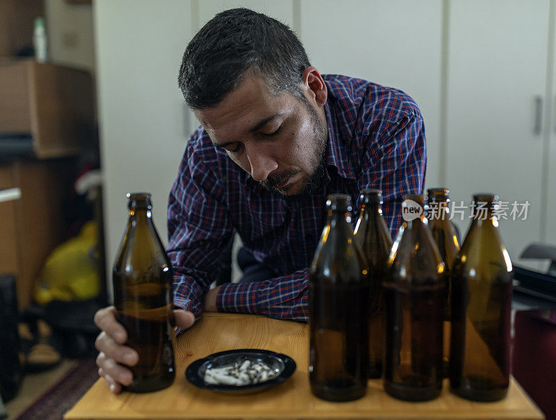 年轻悲伤的醉酒男子喝啤酒和酒精感到浪费，孤独和绝望的痛苦和情绪压力。人与酗酒、上瘾和男人抑郁的概念。