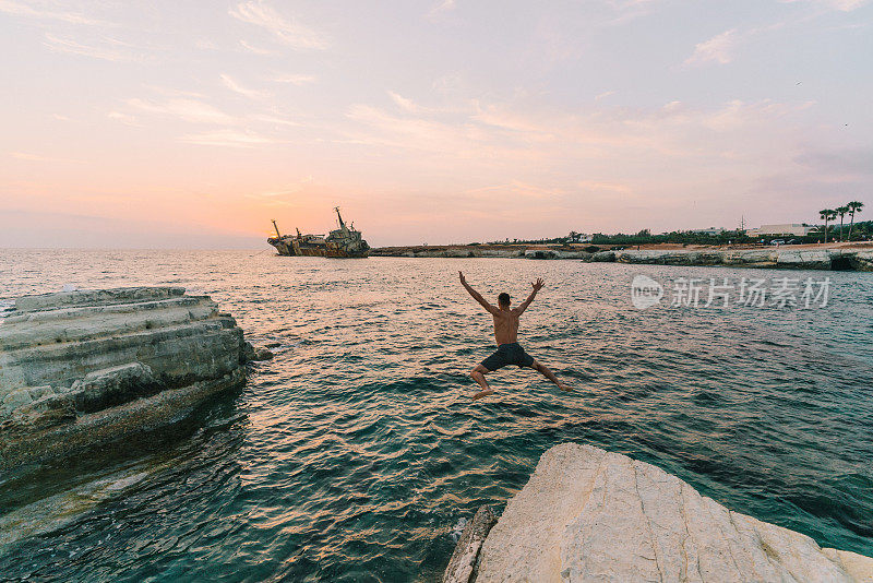 从海边的岩石上跳下的人和塞浦路斯的沉船