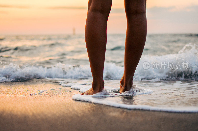 女人的脚踩在海浪上