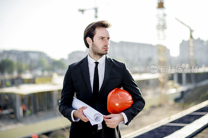 年轻的建筑工程师带着工程和安全帽