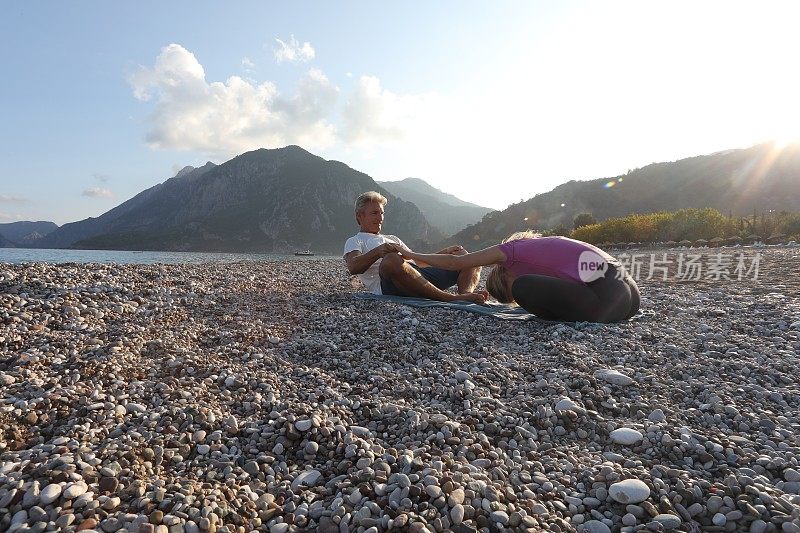 父亲和女儿在海滩上练习日出瑜伽