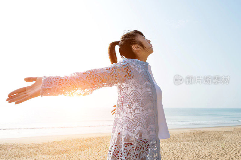 女人站在沙滩上，双臂张开