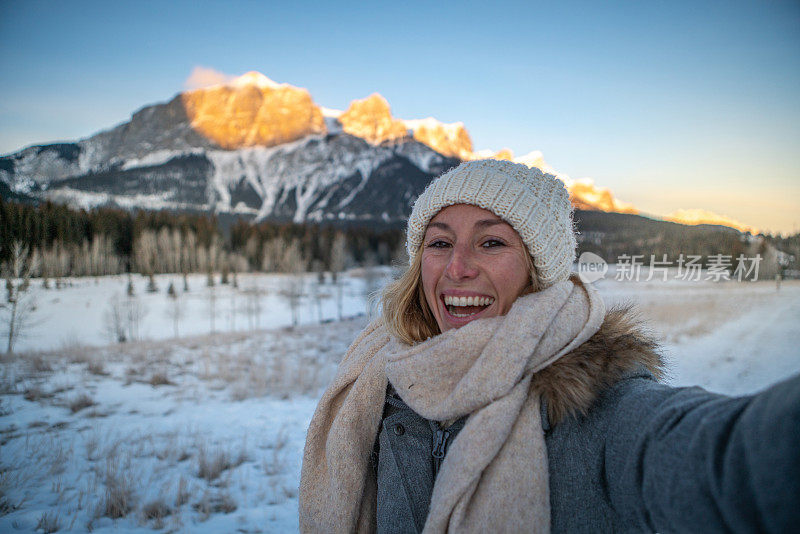 年轻女子在冬天与雪山景观自拍;人们在寒假里玩得很开心