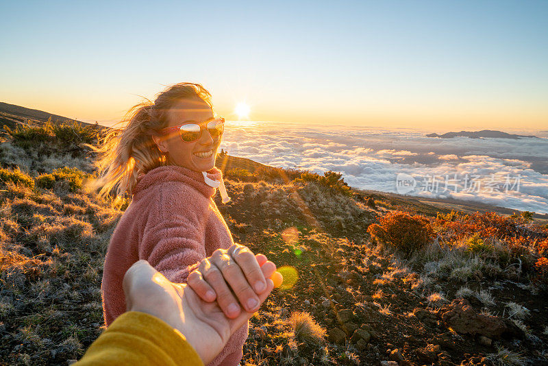 跟我来概念;一个年轻的女人在太阳的云层上带着男朋友去火山