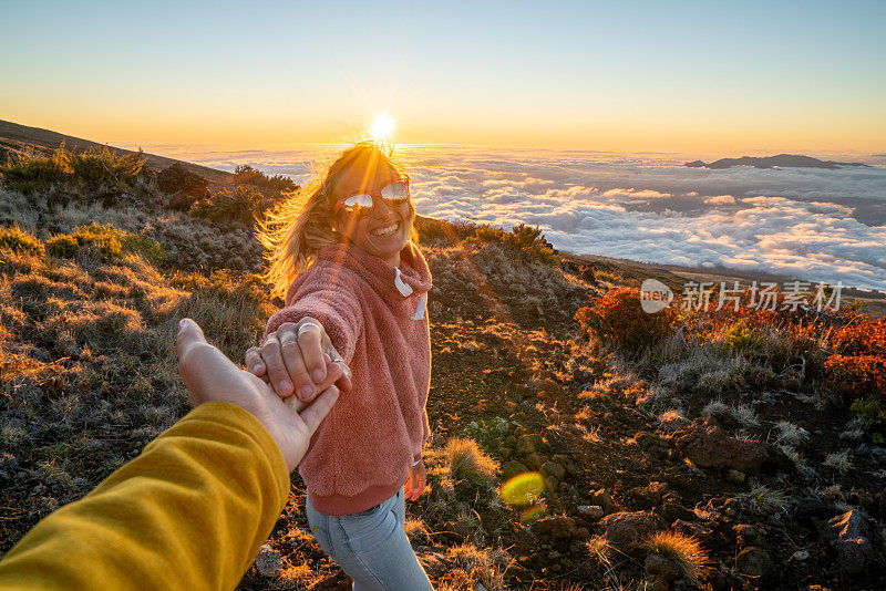 跟我来概念;一个年轻的女人在太阳的云层上带着男朋友去火山