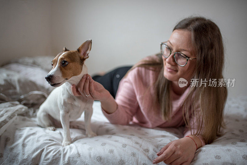 一个年轻的女人和她的小狗杰克罗素梗狗玩耍