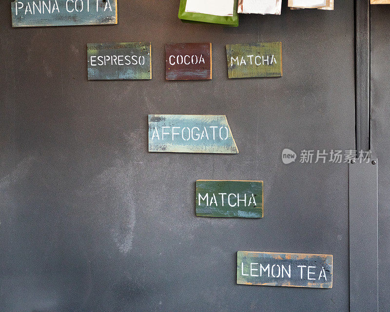 咖啡店的深色墙壁上挂着咖啡和茶的招牌