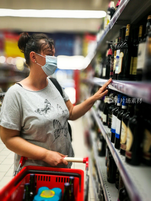 戴着防护口罩在超市买酒的妇女