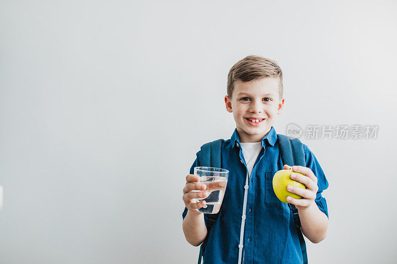 一个拿着水和苹果的小男孩的肖像