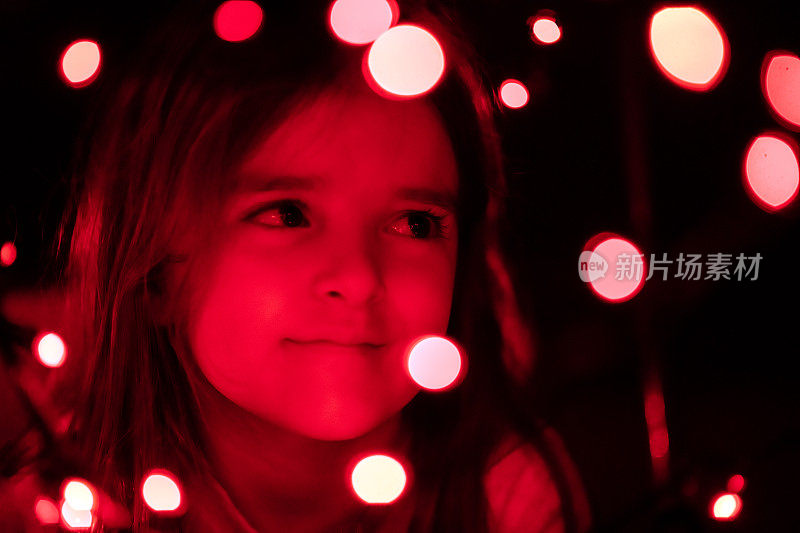 小女孩在黑暗中用红色的柏克圣诞灯做梦