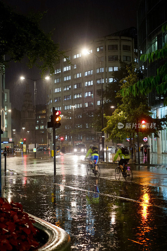 两个骑自行车的人在下雨的街道上