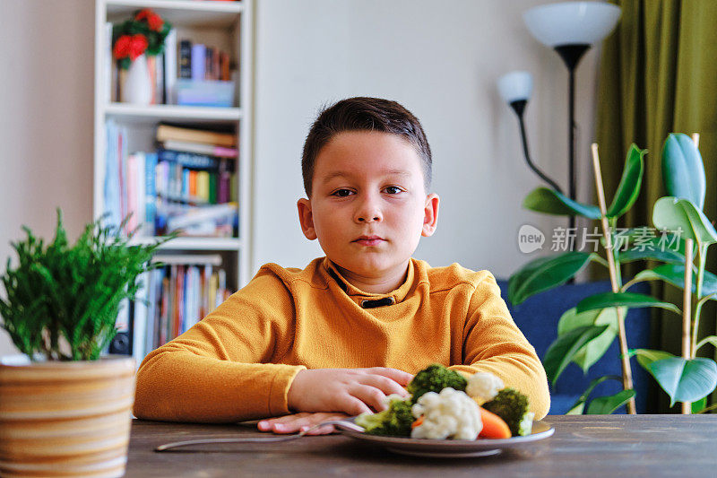 孩子对不得不吃蔬菜很不高兴。他的盘子里有许多蔬菜。他讨厌蔬菜。