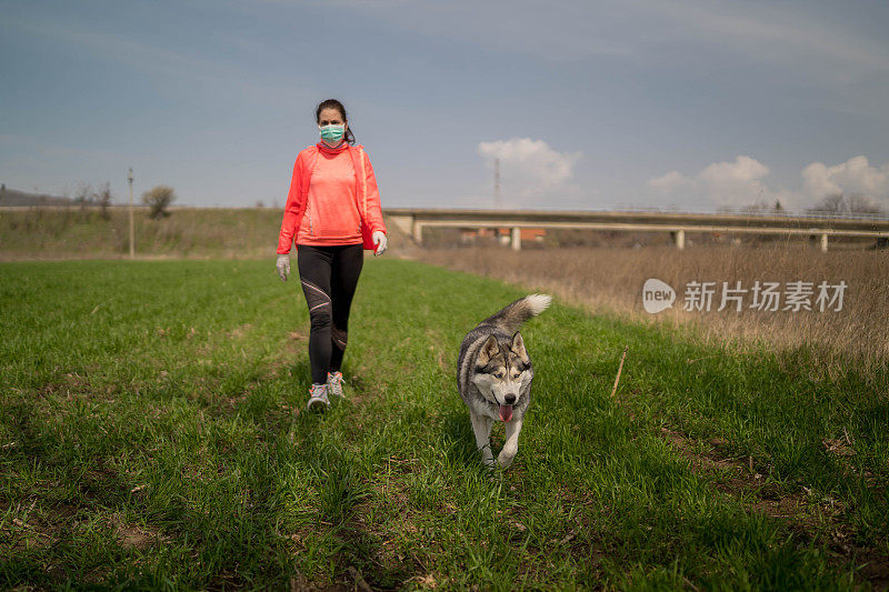 一名妇女在隔离期间带着她的狗在公园散步