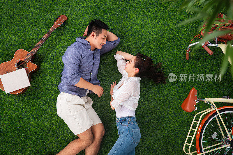 幸福的青年伴侣躺在草地上享受休闲时光
