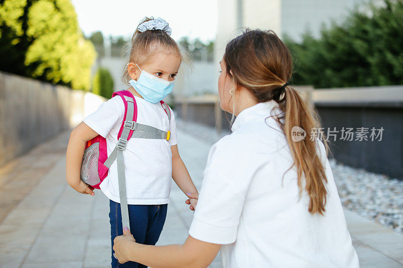 母亲在房子前为孩子准备上学