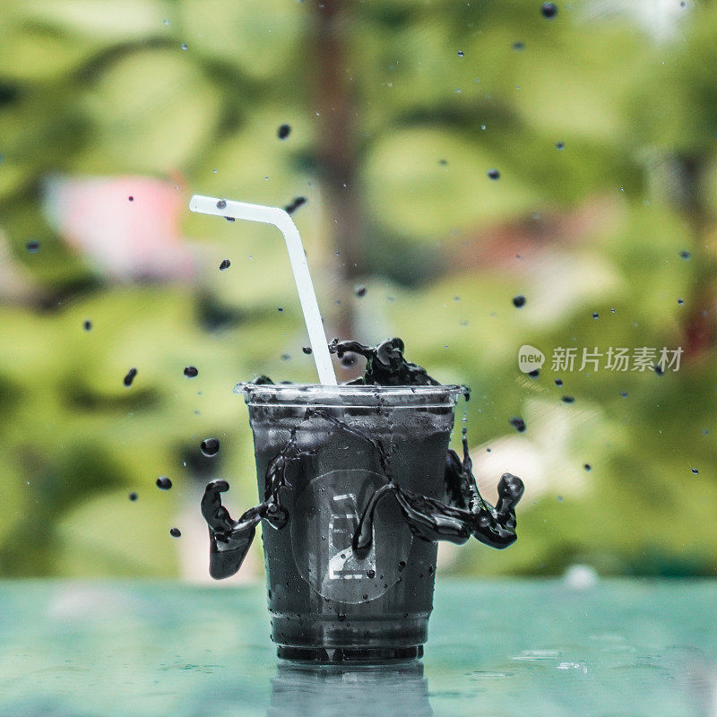 黑色饮料装在塑料玻璃杯中，溅起的水花从玻璃杯中溅起