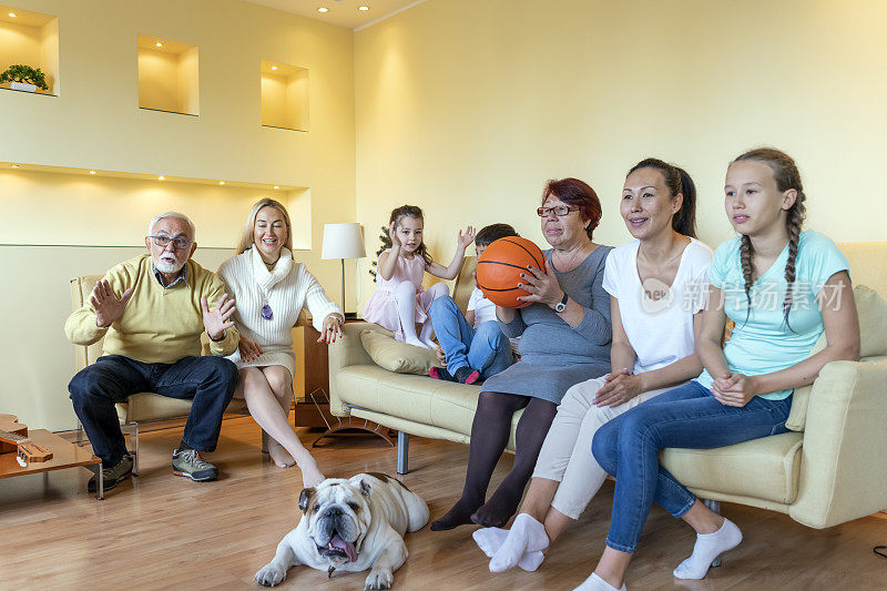快乐的多代同堂在家里看篮球比赛。