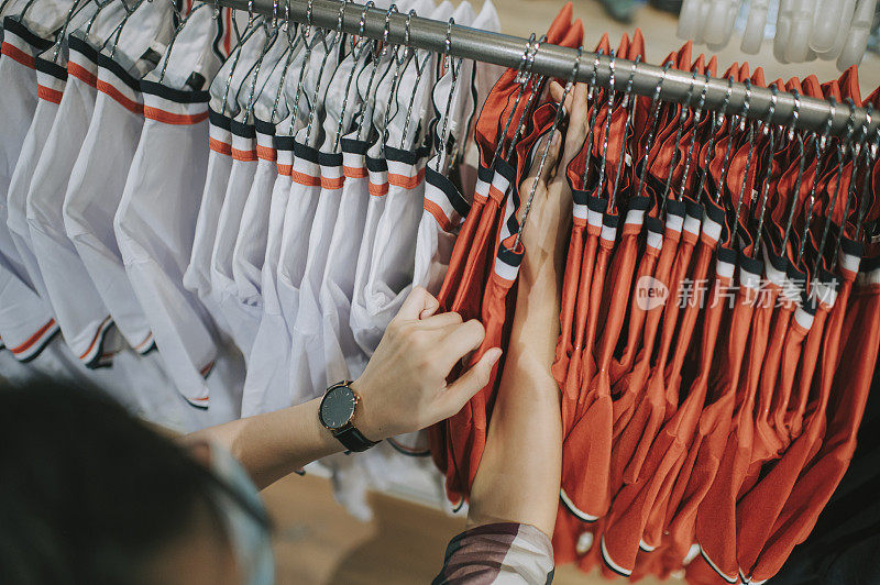 高角度亚洲华人男性手拿男装衬衫在服装店试着选择正确的一件购物