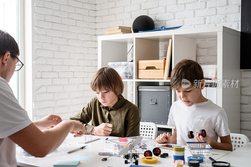 小男孩和老师在车间里建造机器人车