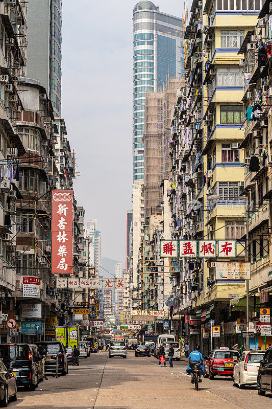 香港九龙孟角街道上的旧公寓楼与现代摩天大楼形成鲜明对比