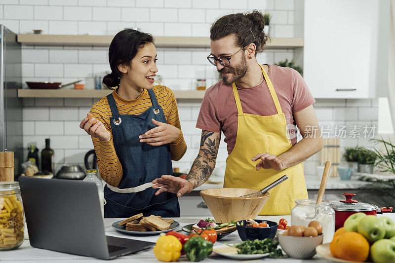 幸福的年轻夫妇在家里准备美味的食物。库存图片