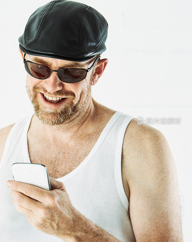 穿着汗衫的中年男子对着手机笑得很开心