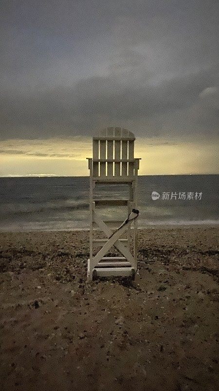 沙滩上的救生员椅在阴天黄昏的天空下