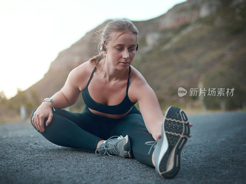 一个年轻女子在户外跑步前伸展的照片