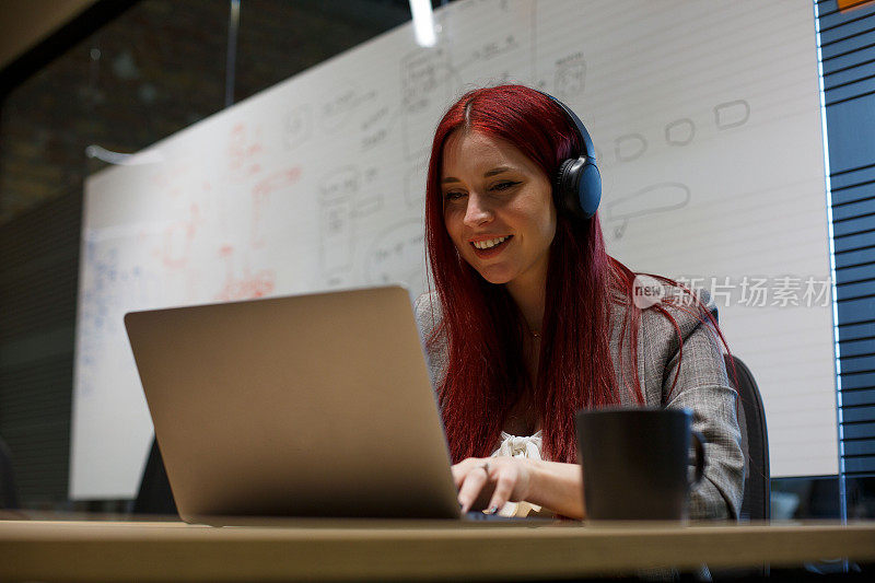 一个红头发的年轻女人正坐在办公室里进行在线会议。