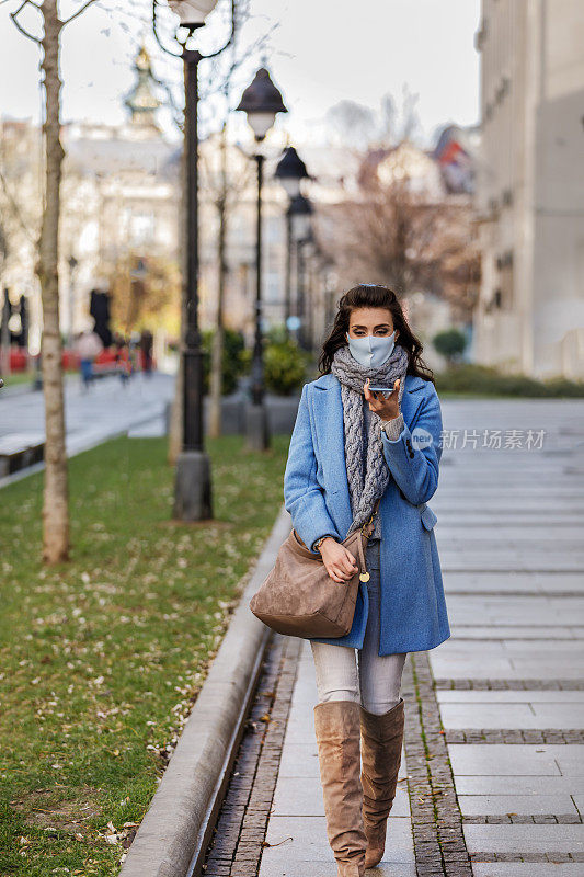 一名年轻的白人妇女在流行病流行期间穿过街道。