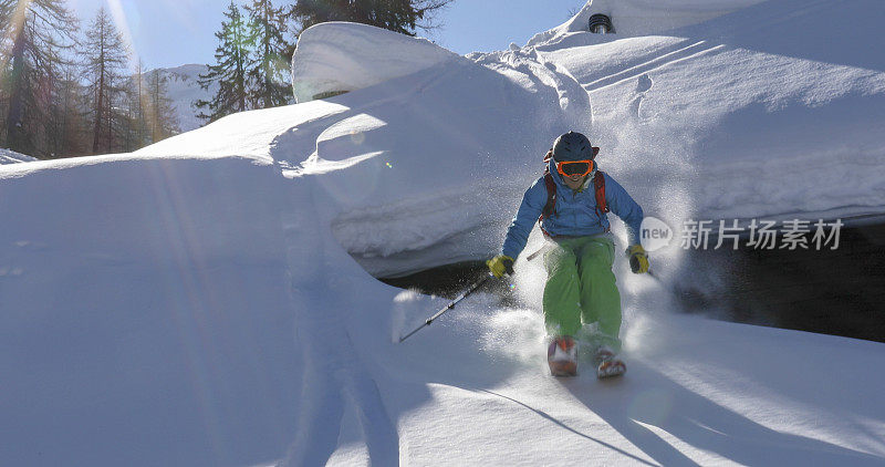 偏远地区的滑雪者从被雪覆盖的岩石上滑下来