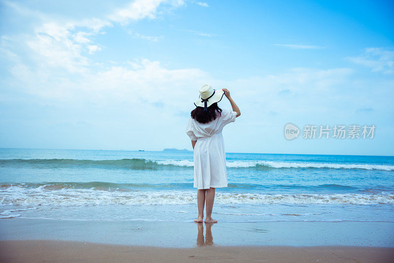 年轻女子站在沙滩上望着大海