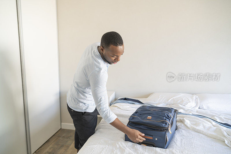 在酒店房间里，一名黑人正在打包随身行李