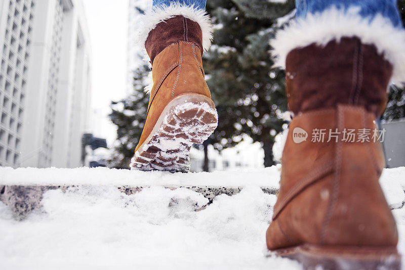 近距离拍摄的低角度的观点，妇女的靴子走在雪地上