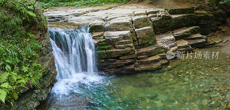 在夏季的森林里，山河上的瀑布，白色的泡沫水从岩石中落下。