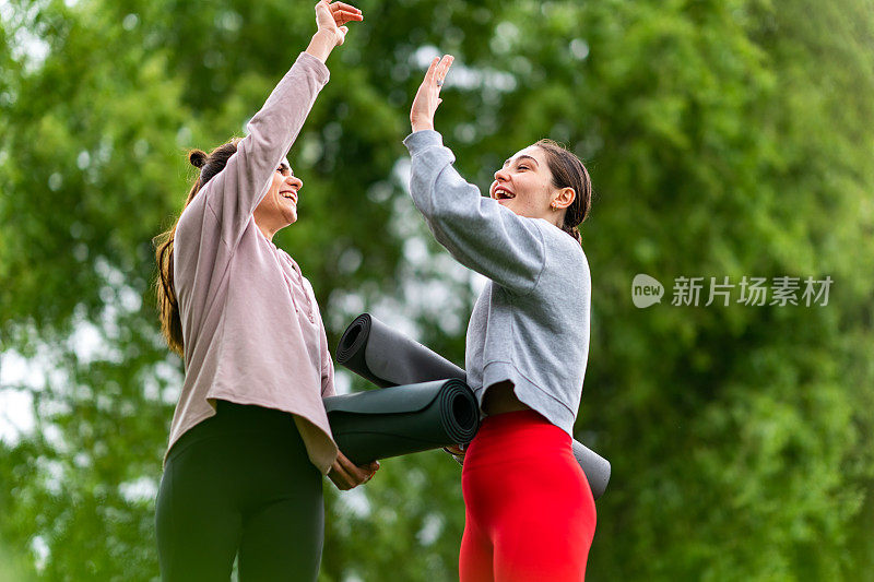 两名女性拿着运动垫在户外散步