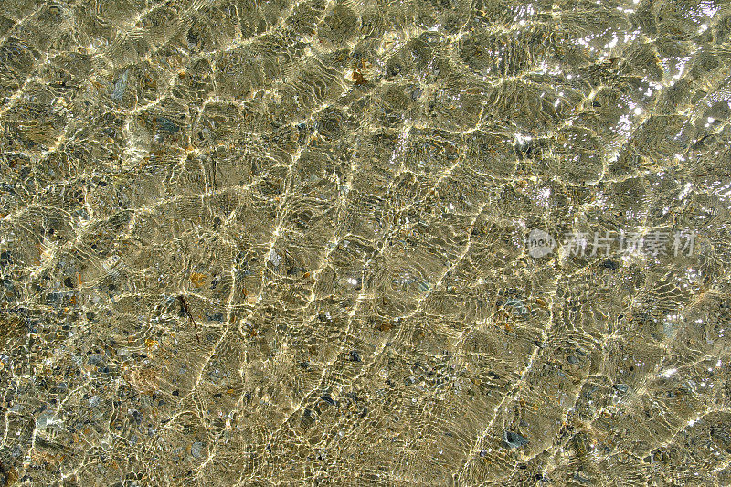 沙质的海底有着最纯净透明的海水，阳光在海浪上闪耀。抽象的背景。