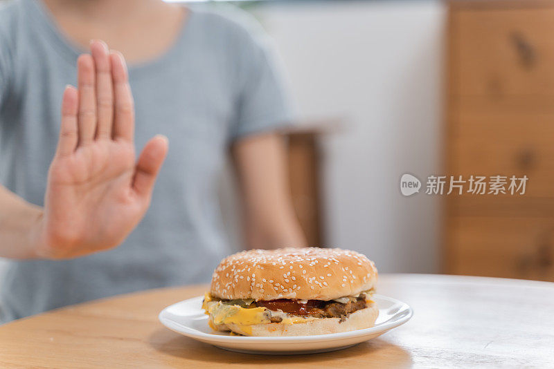 不认识的女人做手势拒绝桌上的汉堡包