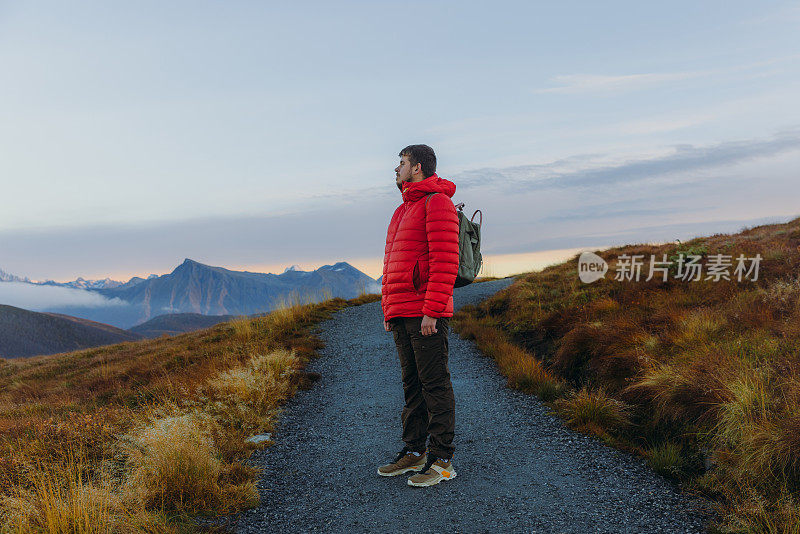 一个背着双肩包的男人在挪威的山上思考日落徒步旅行的侧视图