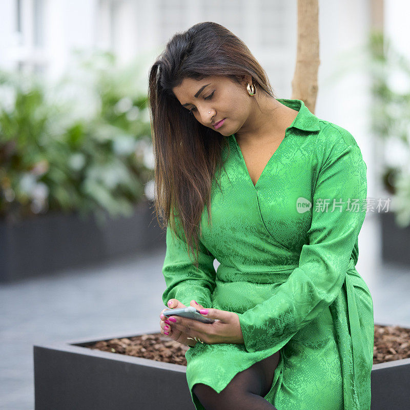 穿绿色衣服的女人检查移动设备