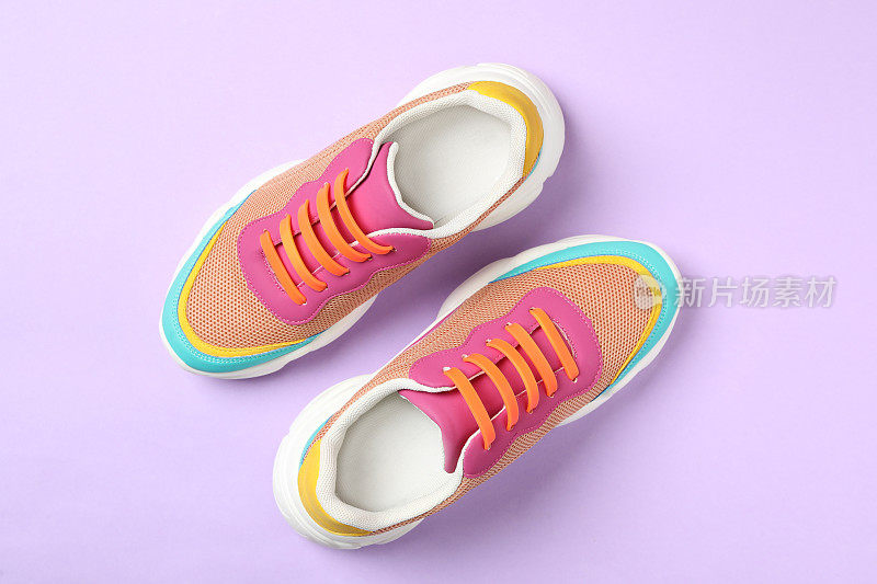 时尚运动鞋与橙色硅胶鞋带在紫罗兰色的背景，平lay