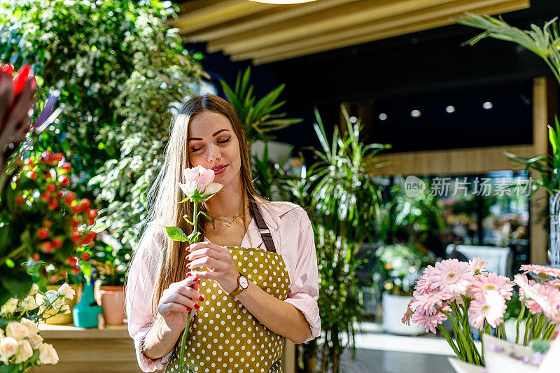 一名女花匠在花店里享受着香气四溢的彩色花朵。