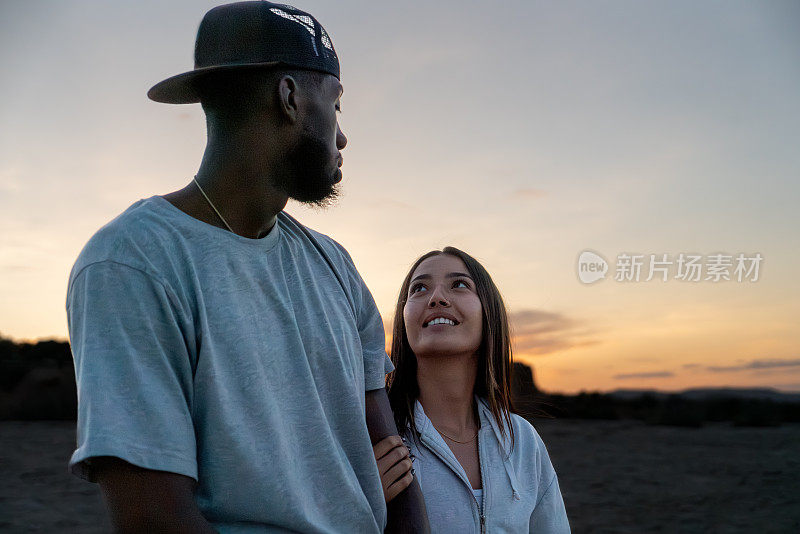 一名年轻的非裔美国男子和一名年轻的西班牙裔女子，手牵手，带着他们忠诚的斗牛犬探索雄伟的科罗拉多国家纪念碑，形成了一幅美丽的多元统一的挂毯。