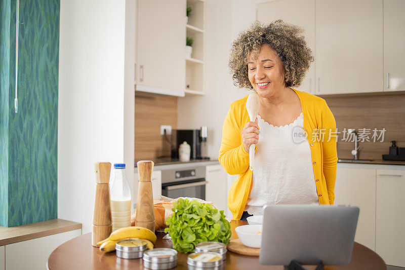 快乐的成熟女人正在厨房里准备一顿健康的饭菜