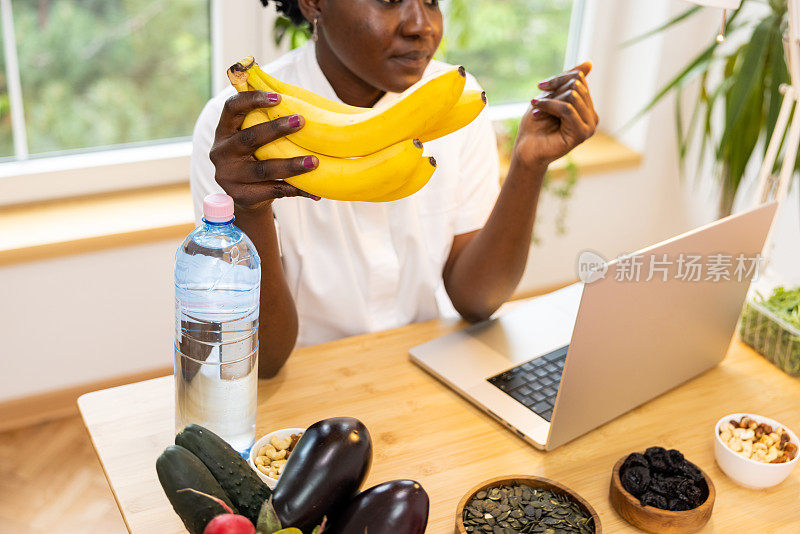 不知名的黑人女性营养学家拿着香蕉解释它们的营养价值